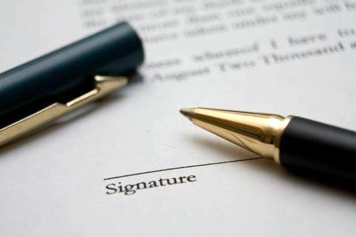open pen lying on a contract requesting a signature