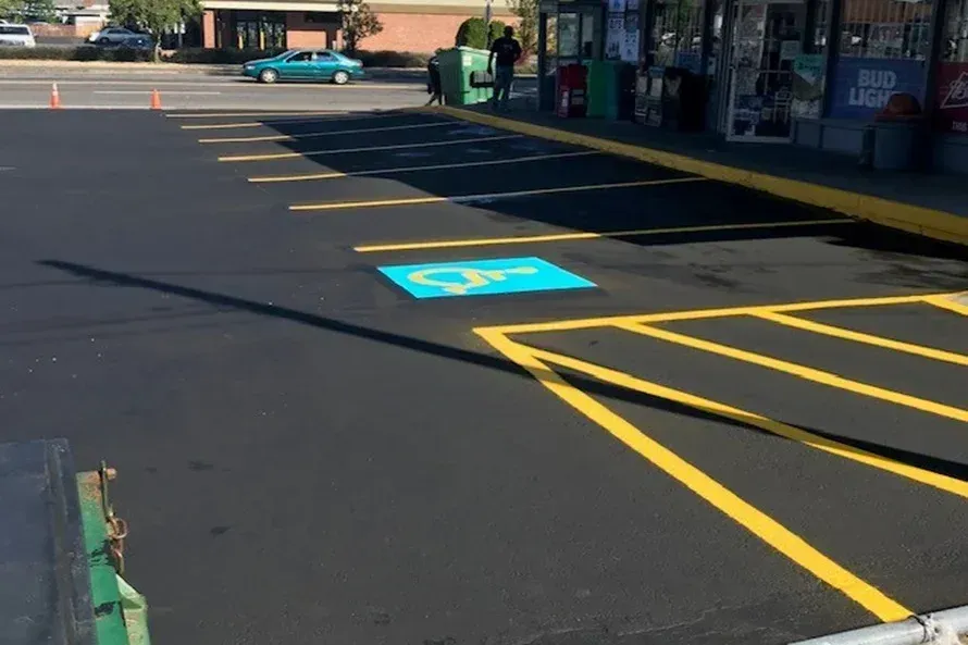 Paved parking lot with handicap spot. A convenience store is in the background.