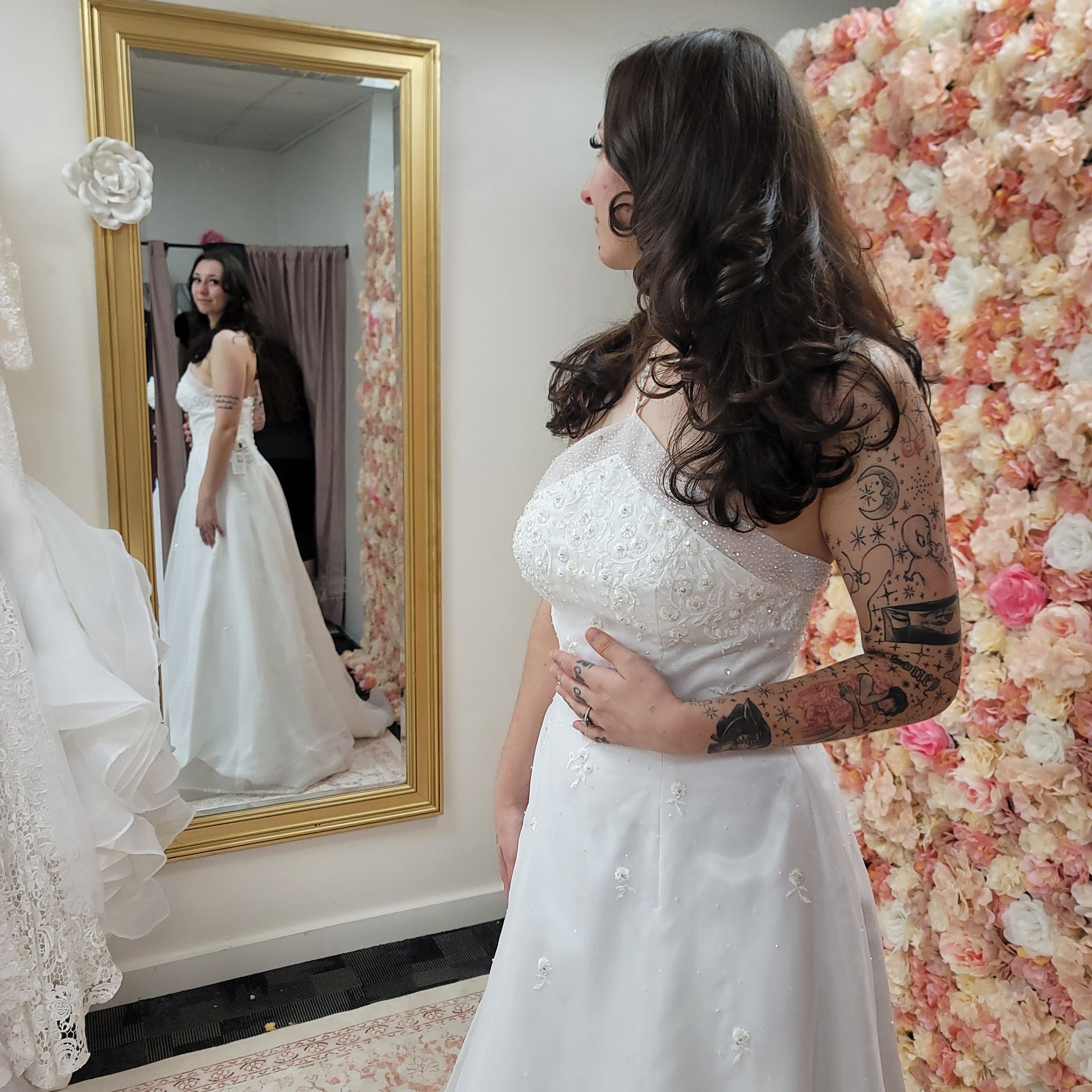 A woman in a wedding dress is standing in front of a mirror