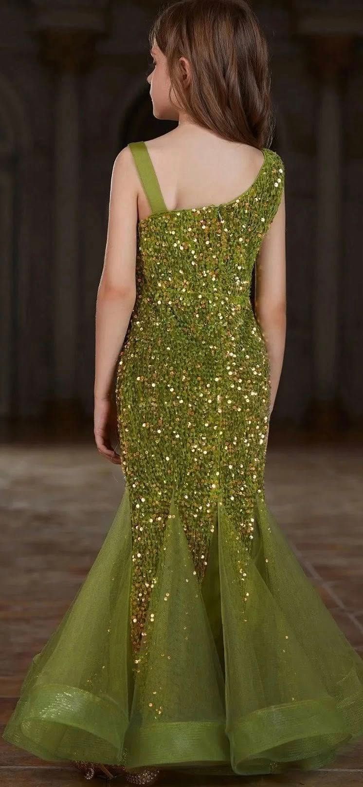 A little girl is wearing a green and gold dress.