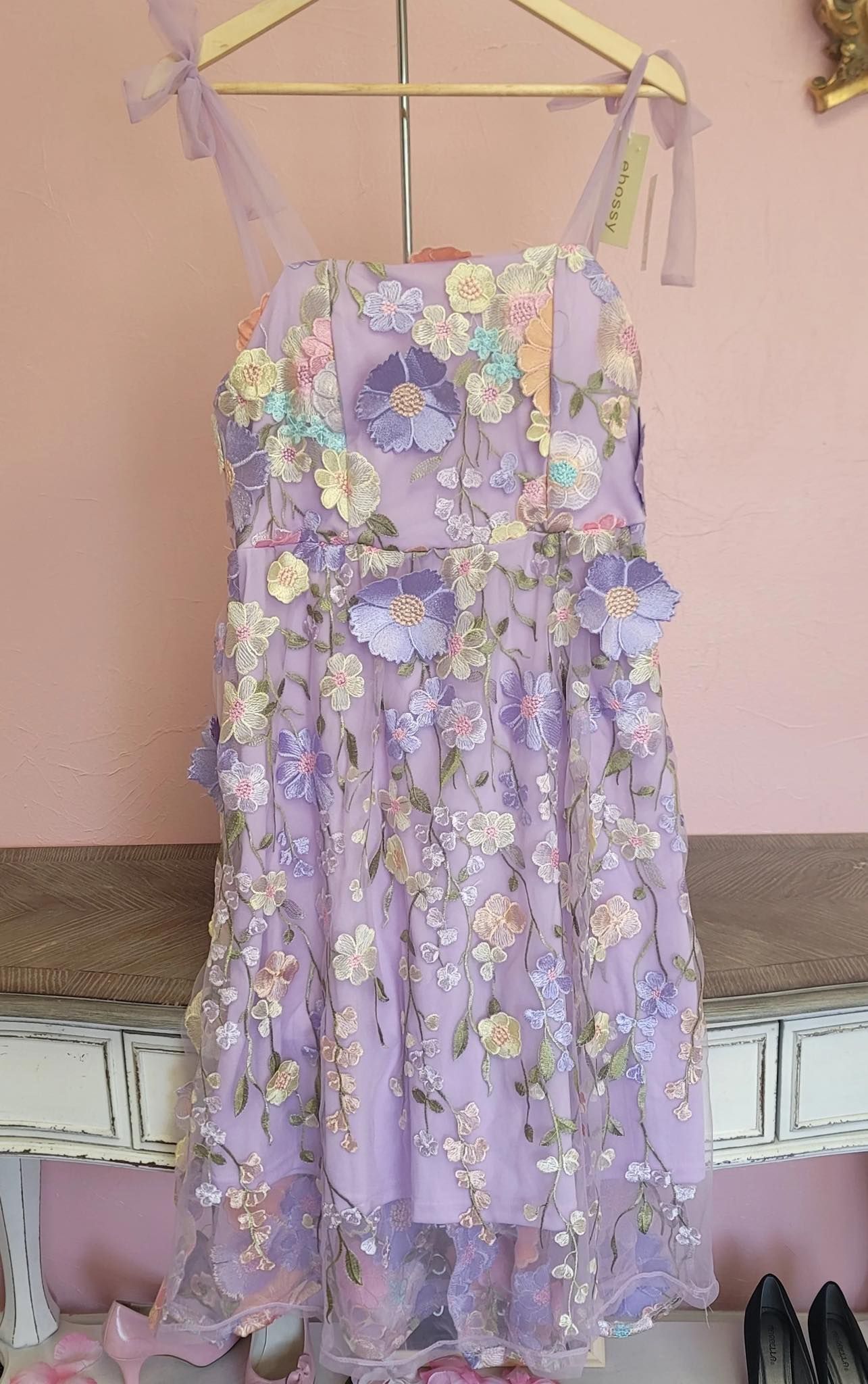 A purple dress is hanging on a wooden hanger