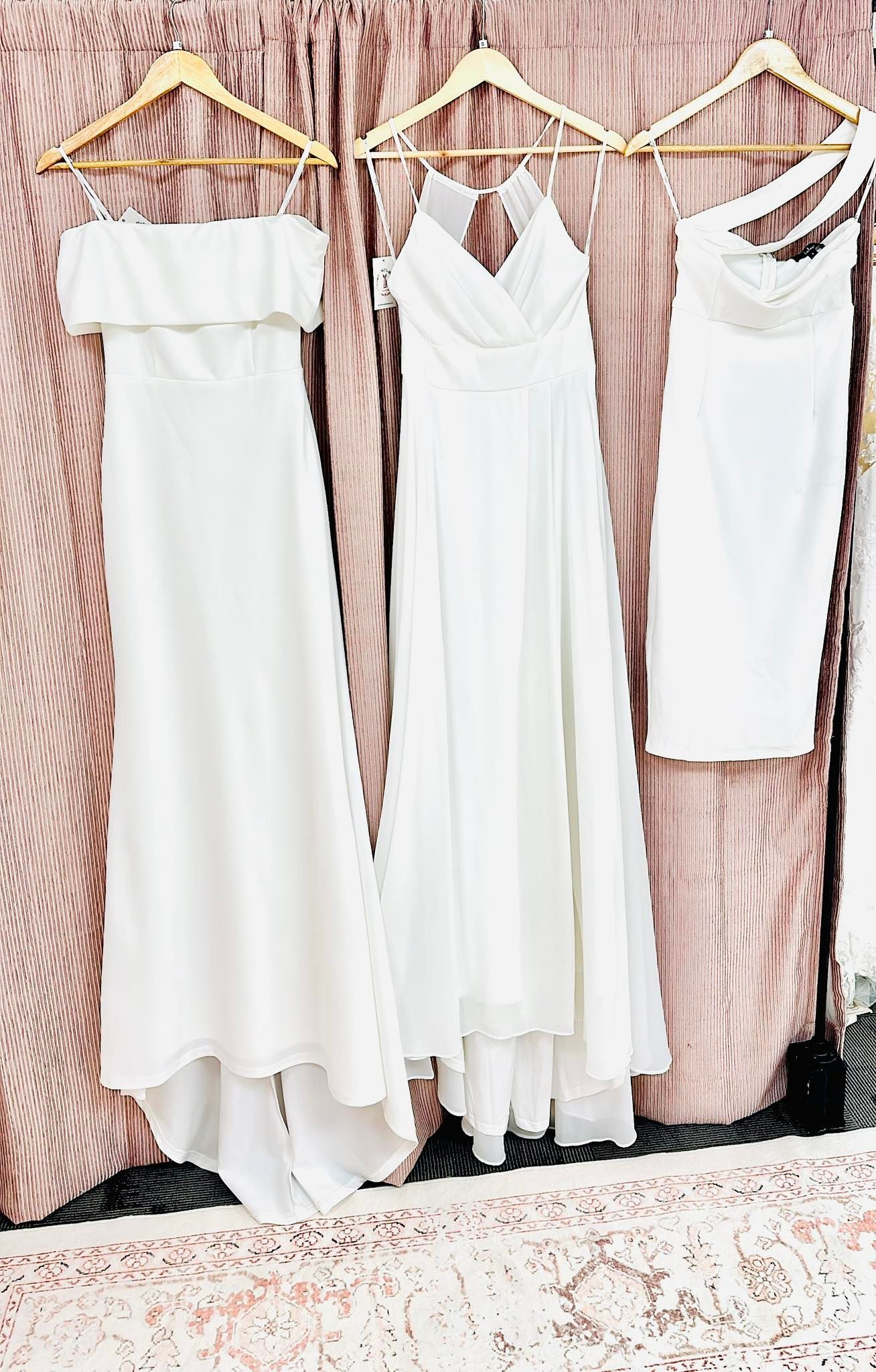 A row of white dresses hanging on a wall.
