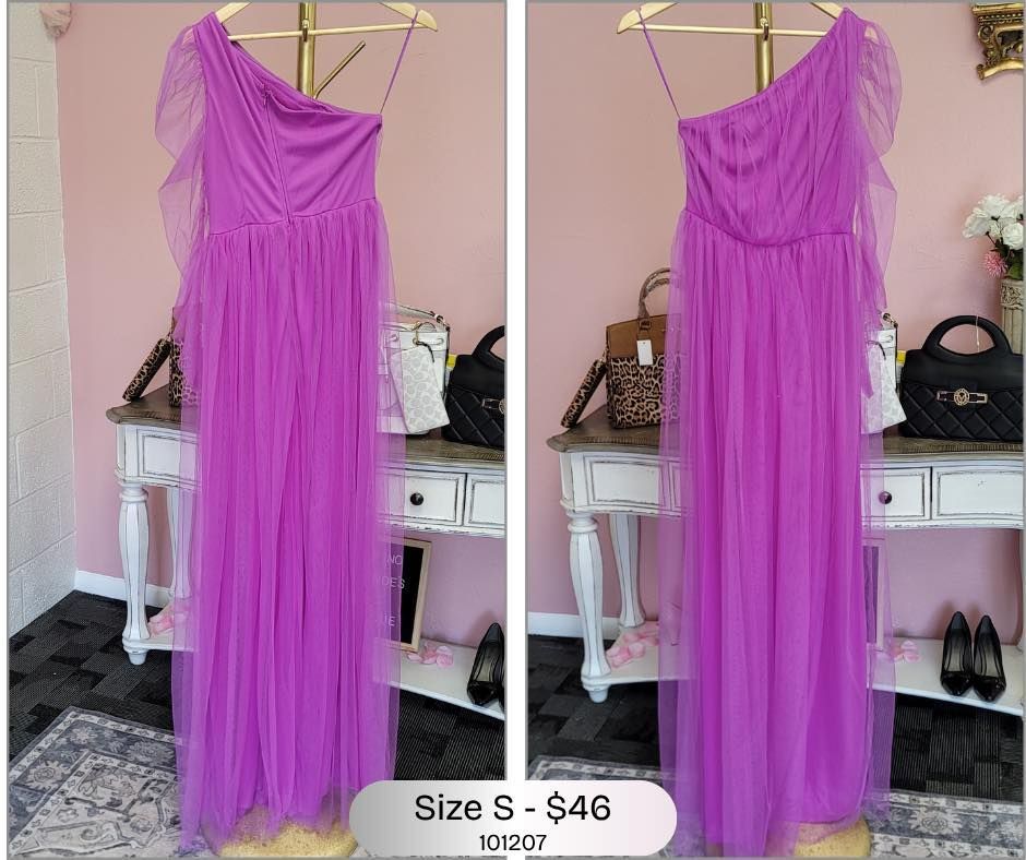 A purple dress is hanging on a hanger in a room.