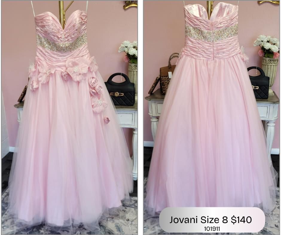 A pink ball gown is hanging on a mannequin in front of a pink wall.