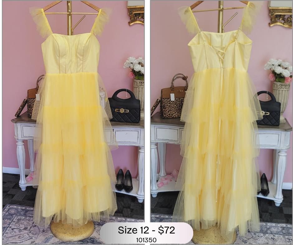 A yellow dress is hanging on a hanger in a room.