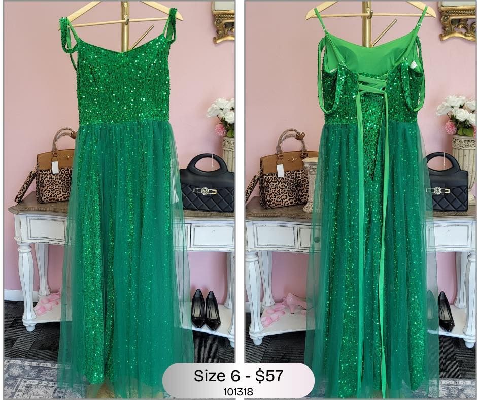 A green dress is hanging on a hanger in a room.