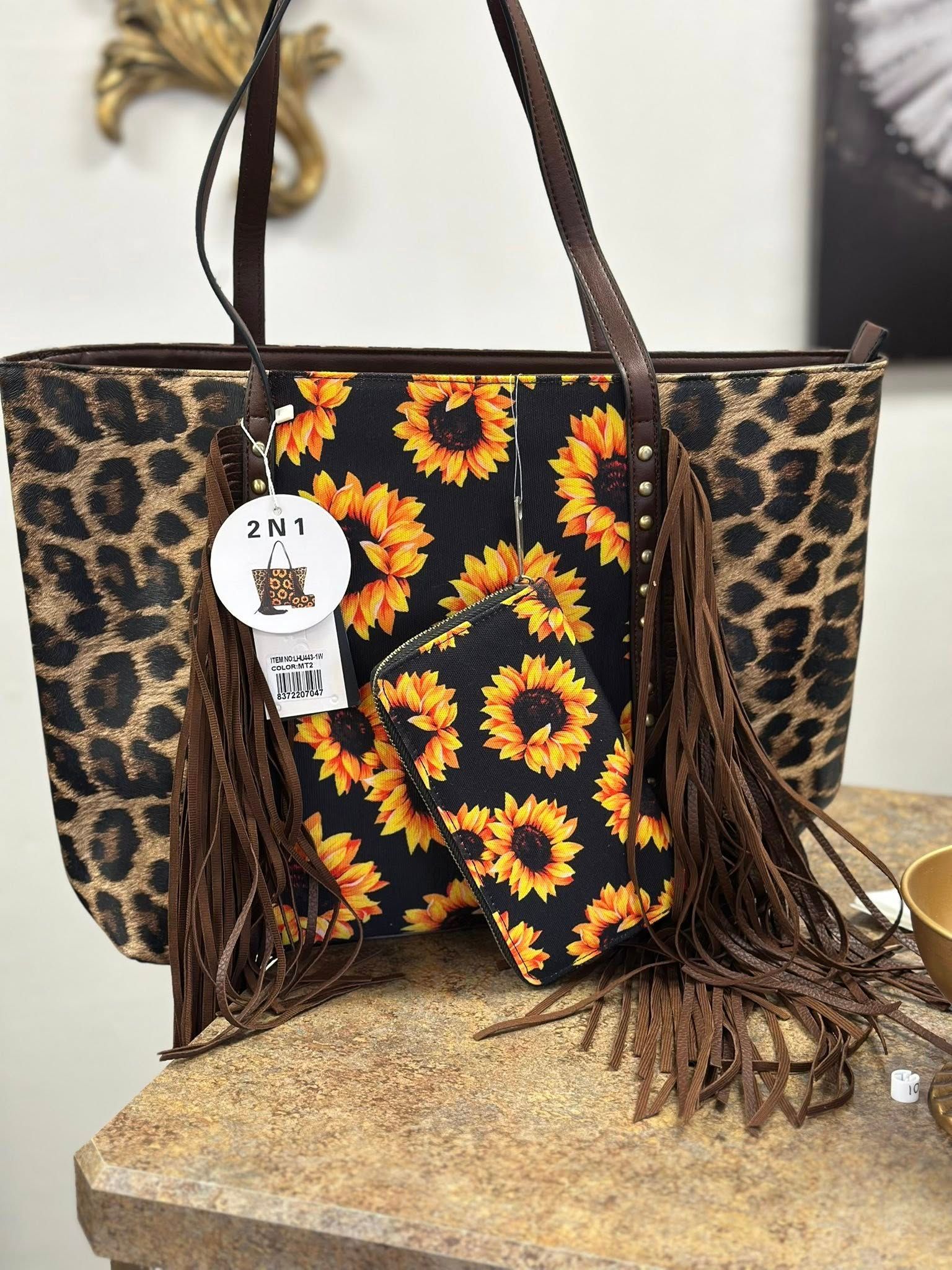 A leopard print tote bag with sunflowers and fringe is sitting on a table.