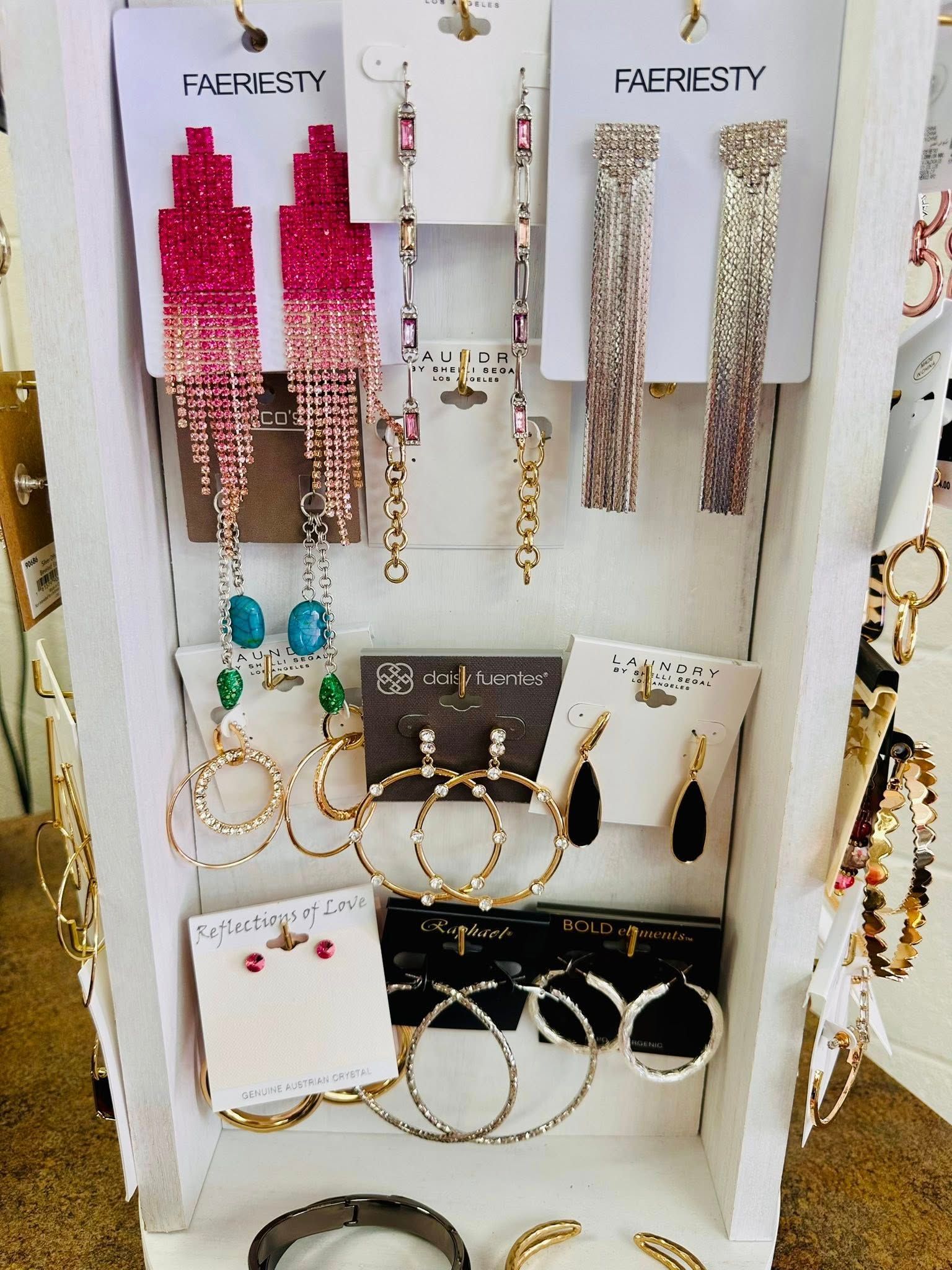 A display of earrings and bracelets including a pair of pink earrings