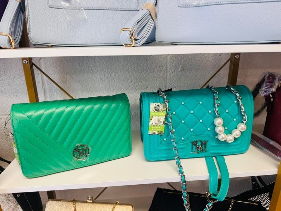 Two green handbags are sitting on top of a white shelf.
