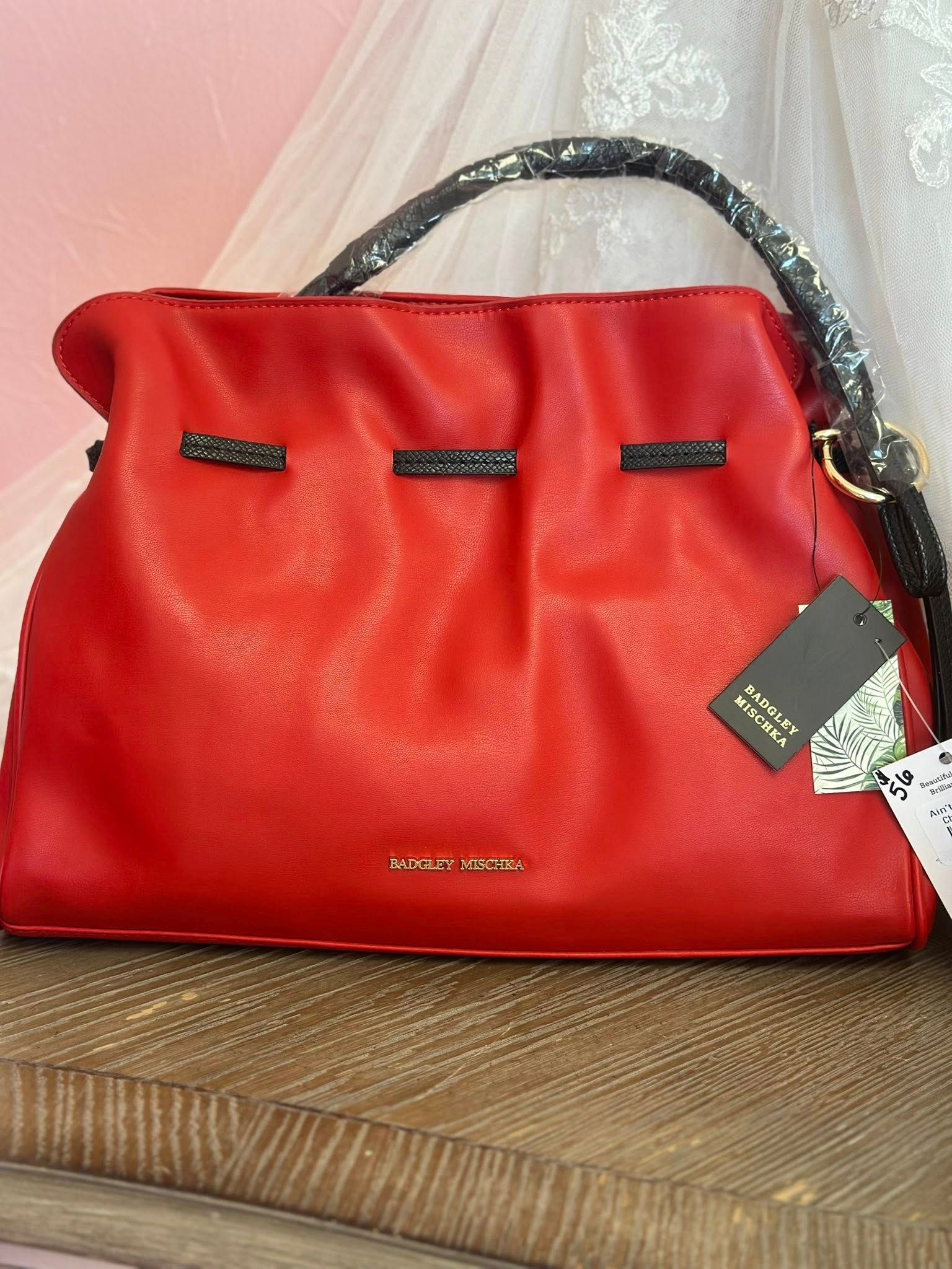 A red purse is sitting on top of a wooden table.