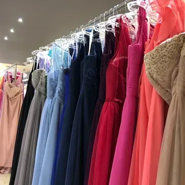 A row of dresses are hanging on a rack in a store.