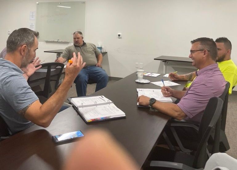 A group of people are sitting around a table looking at blueprints.