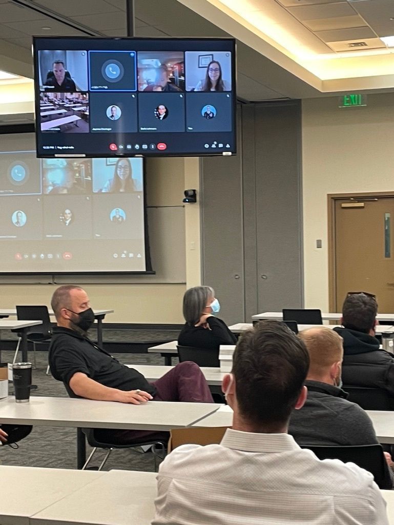 A group of people are sitting around a table with laptops in a conference room.