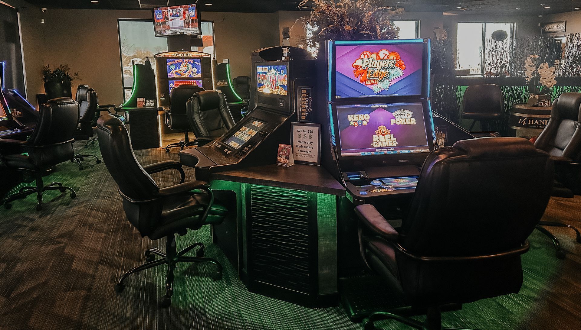 Gaming machines in a casino setting, with black chairs, green lights, and digital displays.