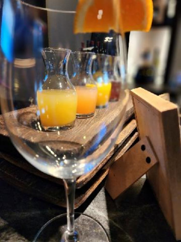 A glass of orange juice sits on a wooden tray
