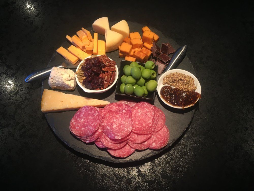 A black plate topped with a variety of meats and cheeses