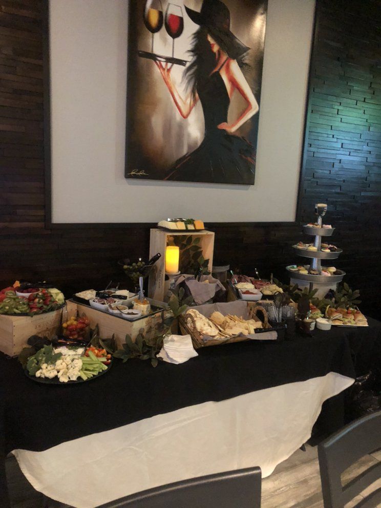 A buffet table with a painting of a woman holding wine glasses