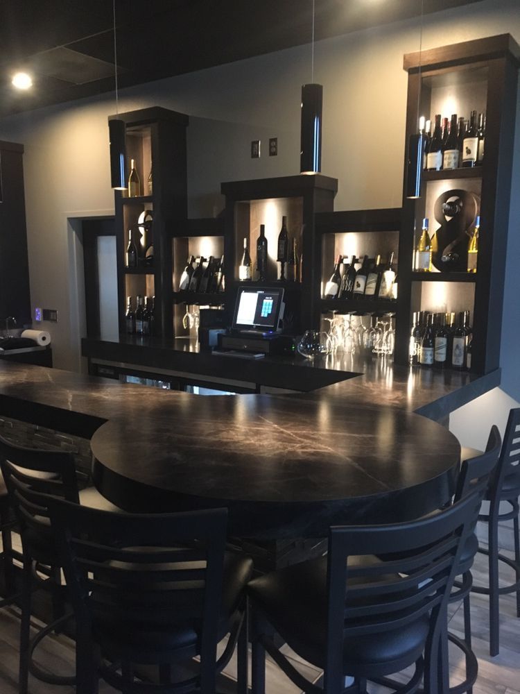A bar with a table and chairs and shelves full of bottles