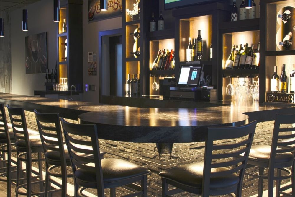 A bar in a restaurant with bottles of wine on shelves