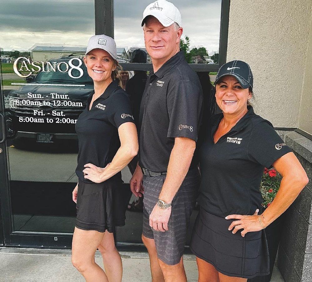 Three people standing in front of a building that says casino 8
