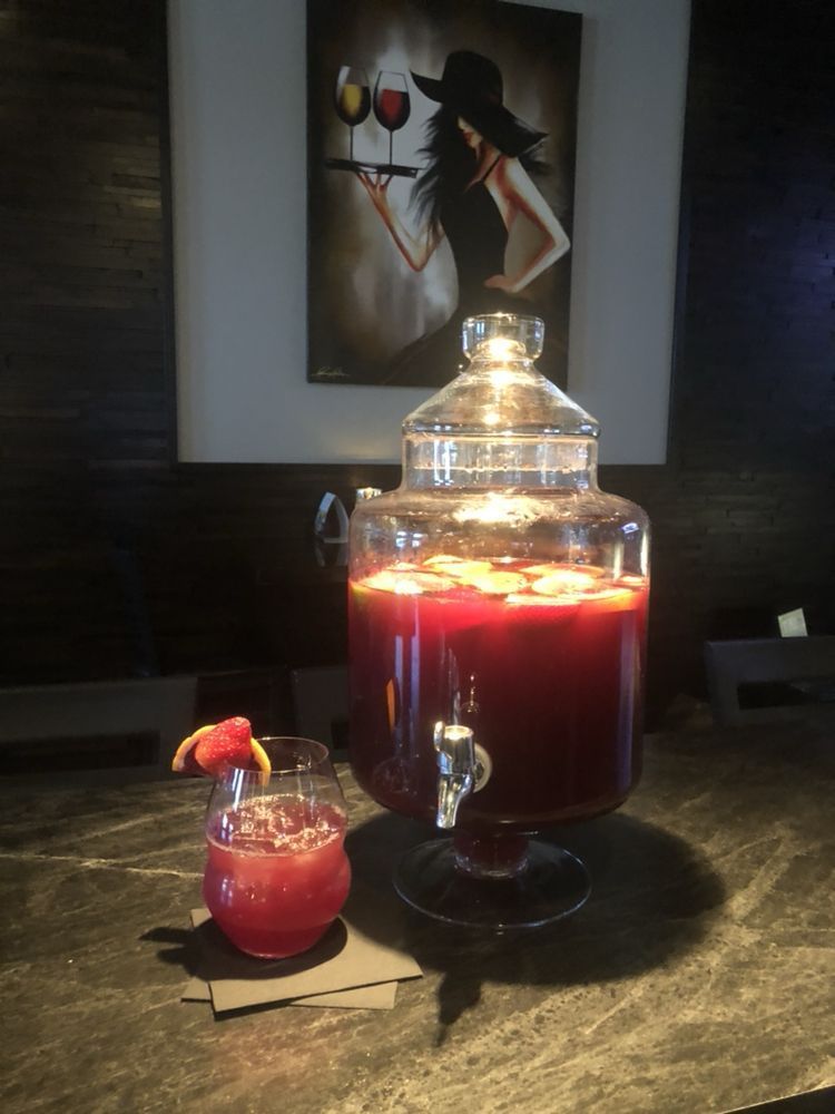 A glass jar filled with red liquid is on a counter next to a glass of red liquid.