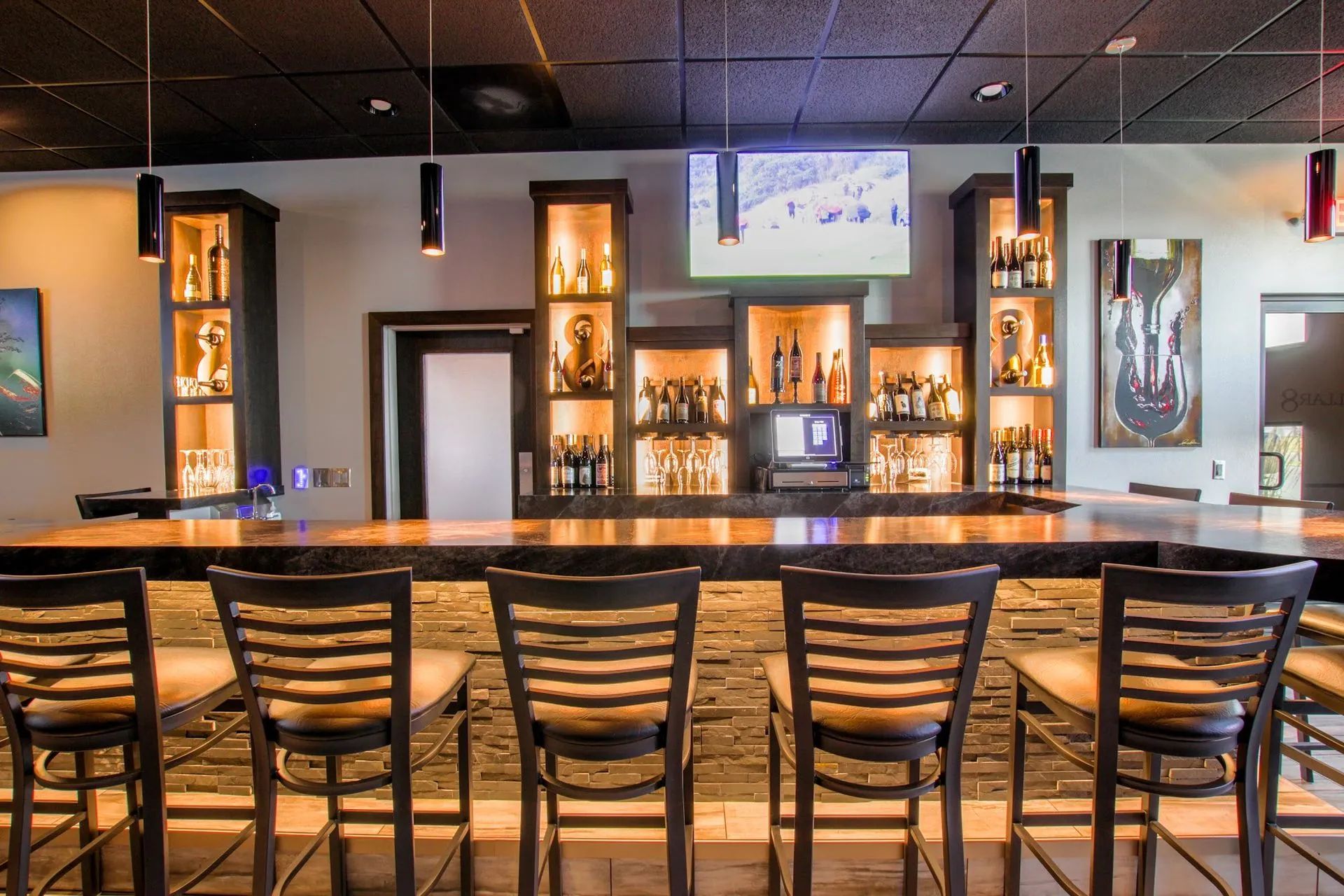 Bar with wooden stools, backlit liquor displays, copper bar, and a TV.
