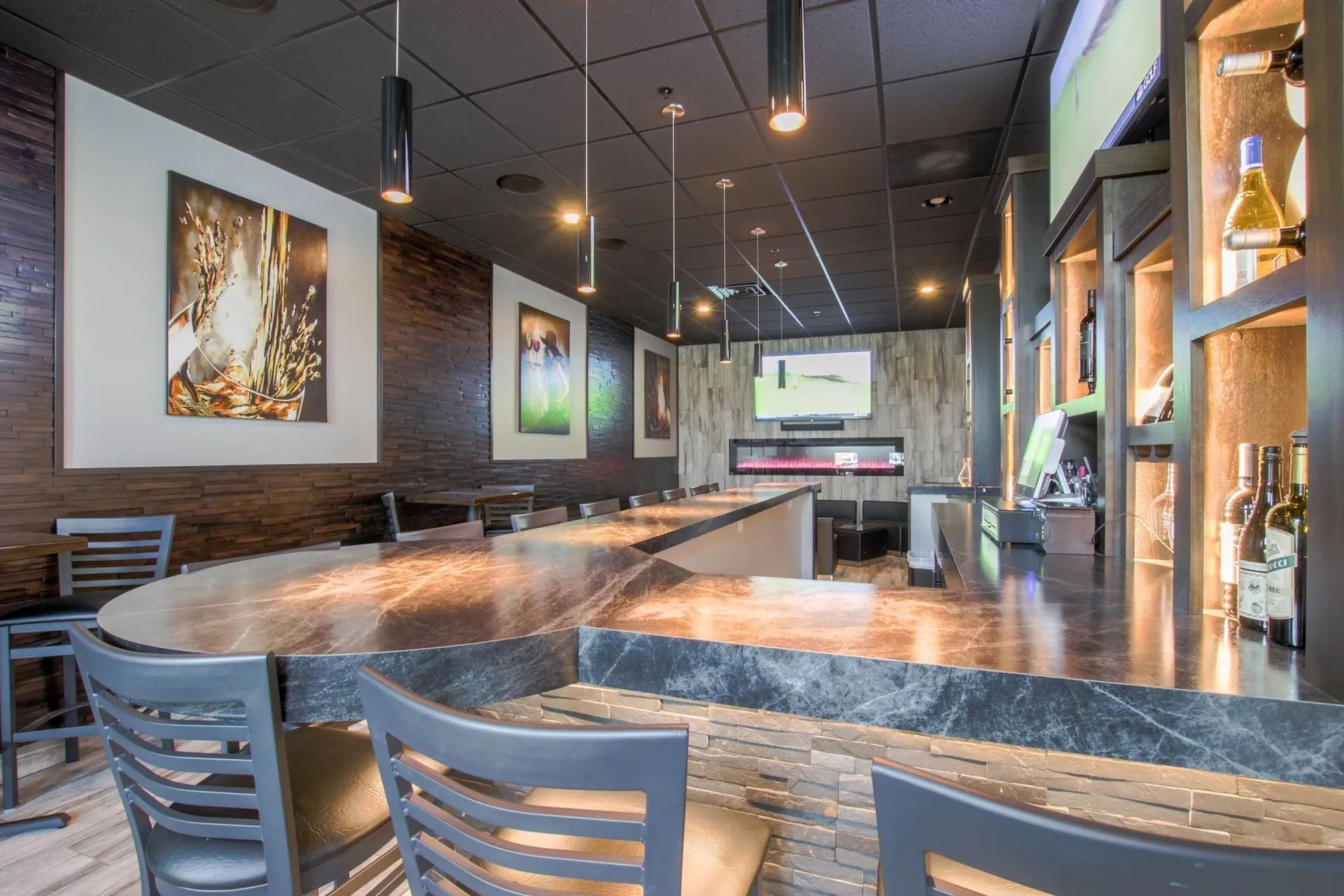 Interior of a bar with a long counter, stools, and artwork on the walls.