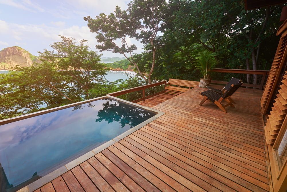 A Wooden Deck with A Swimming Pool in The Background — Radburn Carpentry in Tamworth, NSW