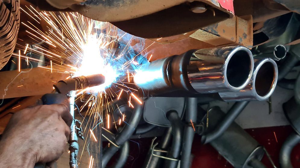 A Person is Welding an Exhaust Pipe on a Car — Fischer Automotive in Svensson Heights, QLD