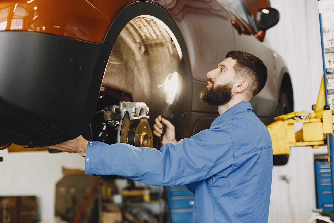 A male car mechanic checks the brakes of a car.