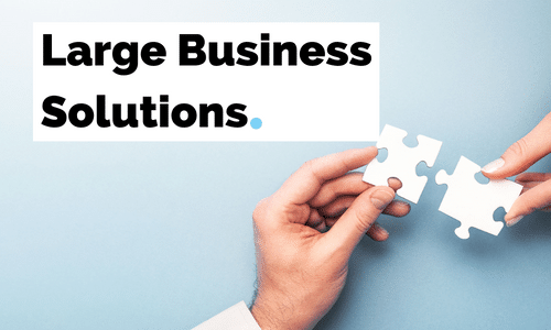 Two people are holding puzzle pieces in their hands in front of a sign that says `` large business solutions ''.