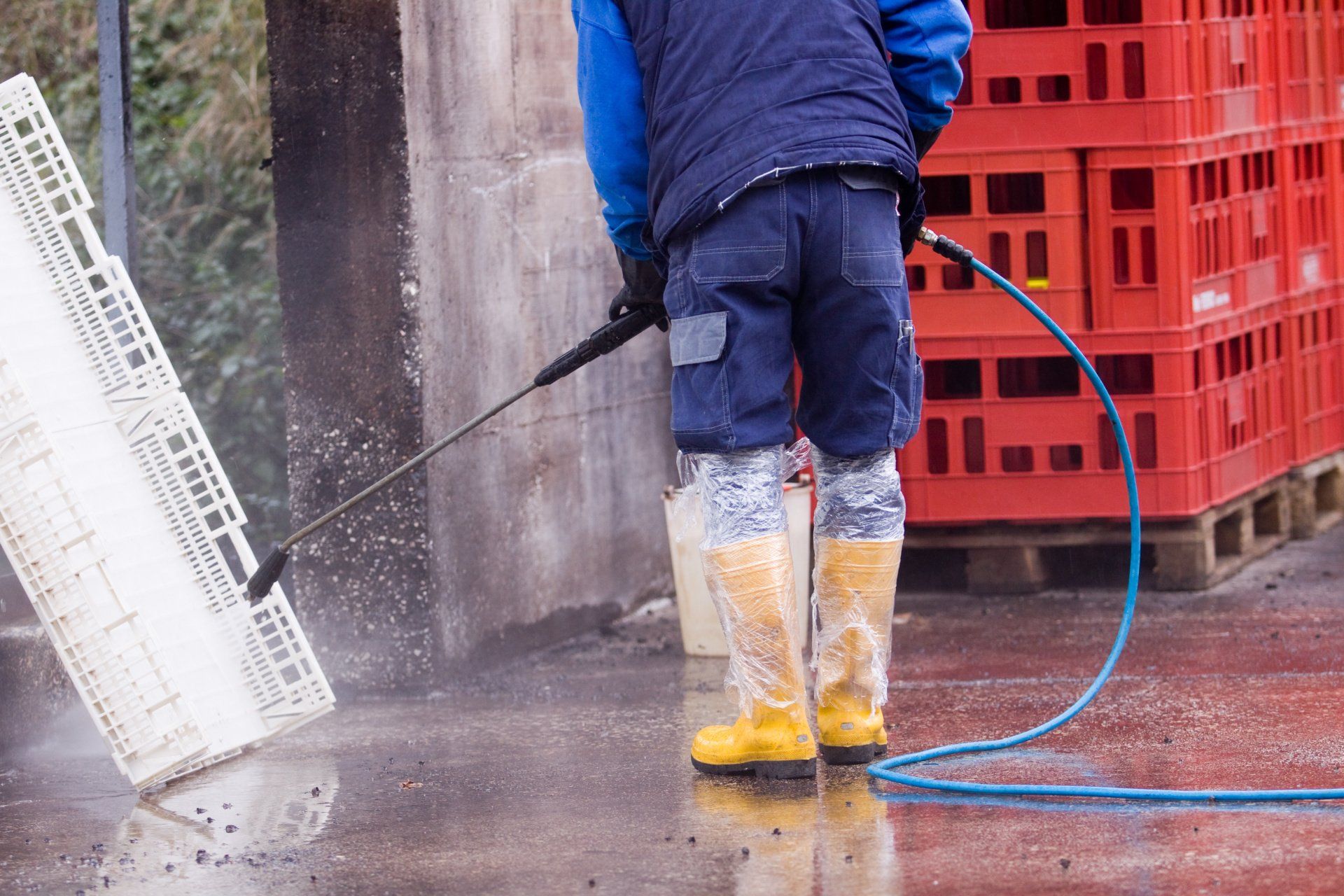 A man is cleaning a crate with a high pressure washer.