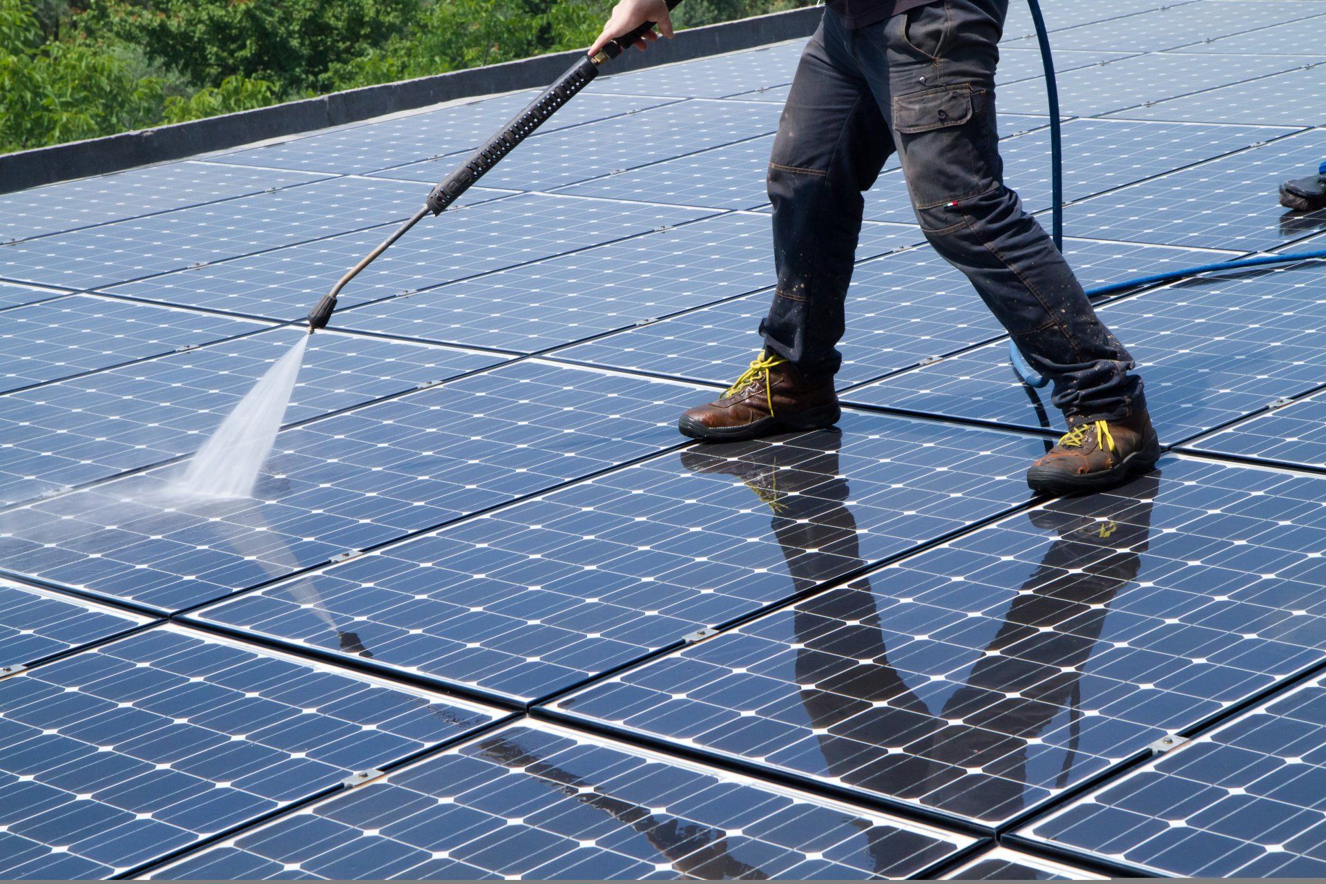 A man is cleaning solar panels with a high pressure washer.