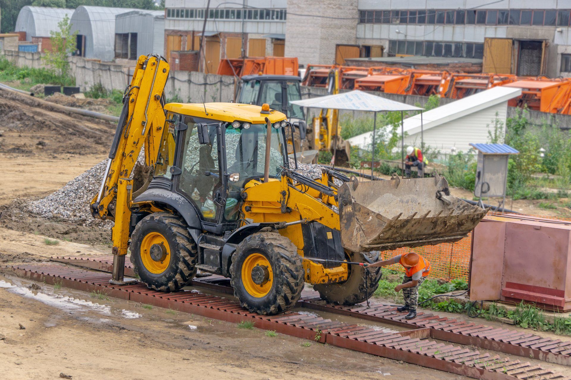 A yellow tractor is driving down a dirt road on a construction site.