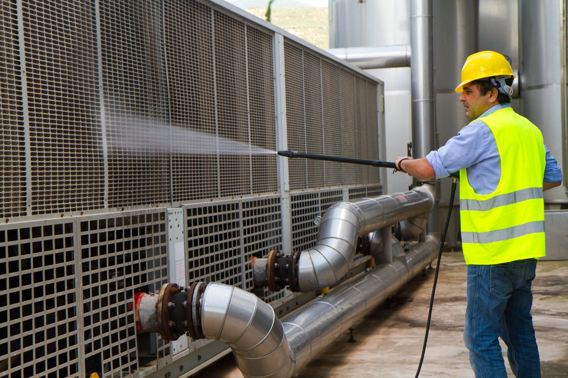 A man is cleaning pipes with a high pressure washer.