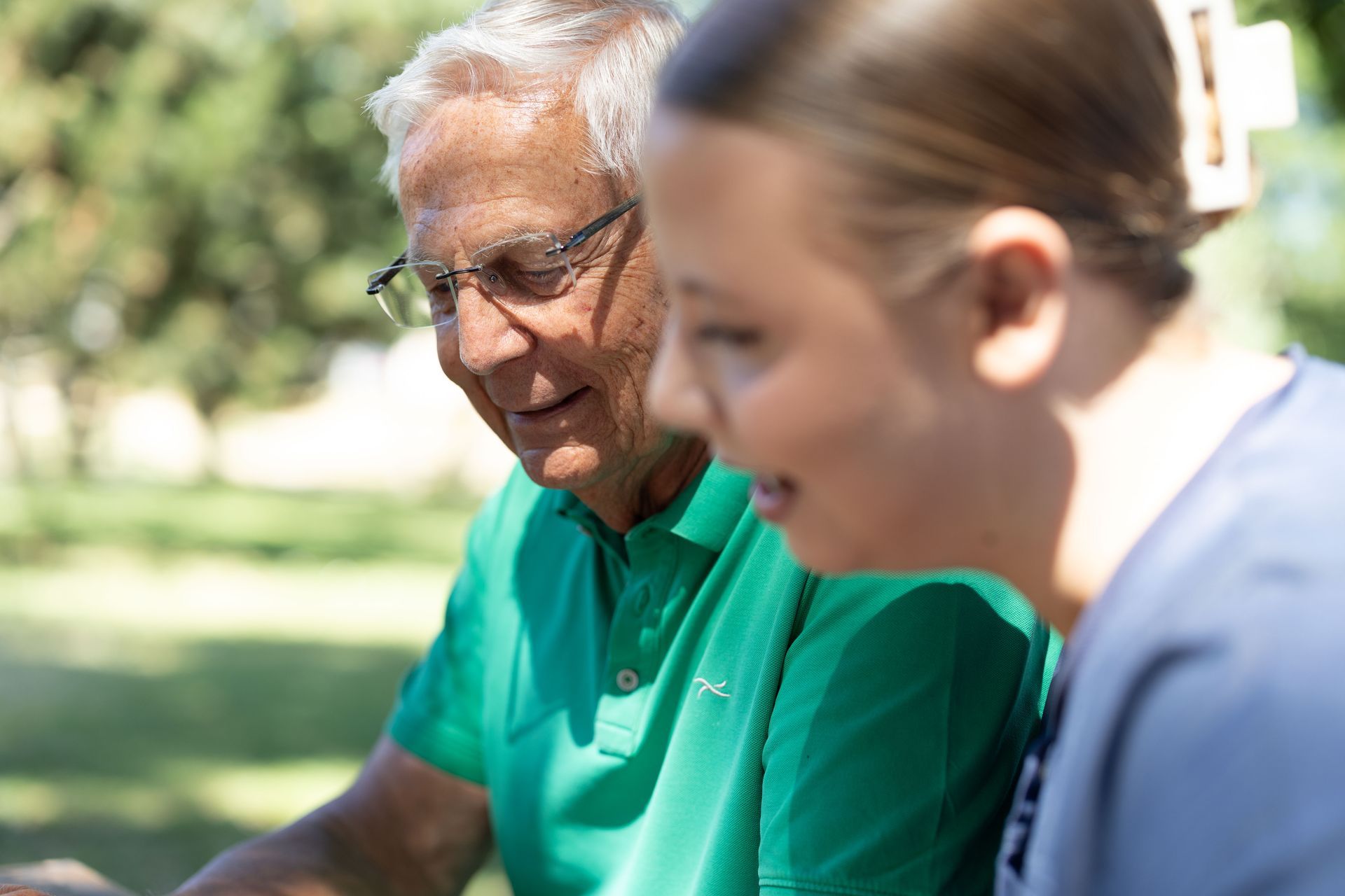 Ein Mann im grünen Hemd und eine Frau schauen sich gemeinsam im Freien etwas an und lächeln.