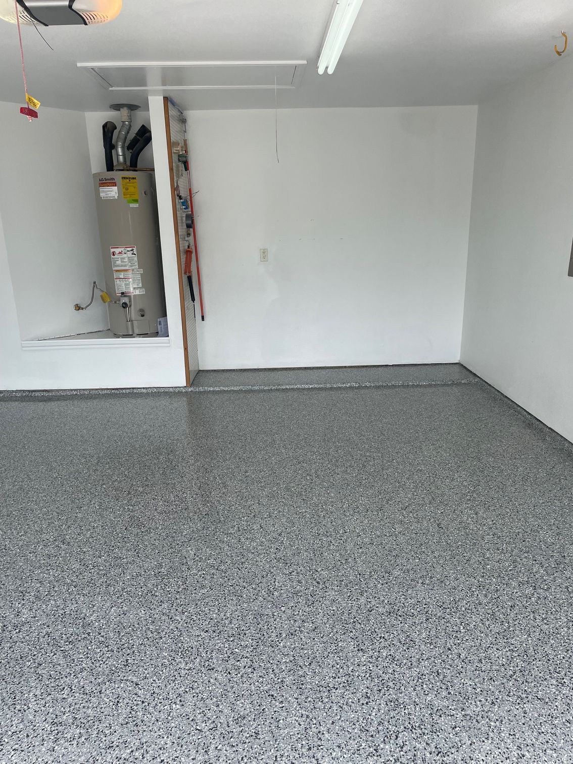 A garage with a water heater and a gray floor.