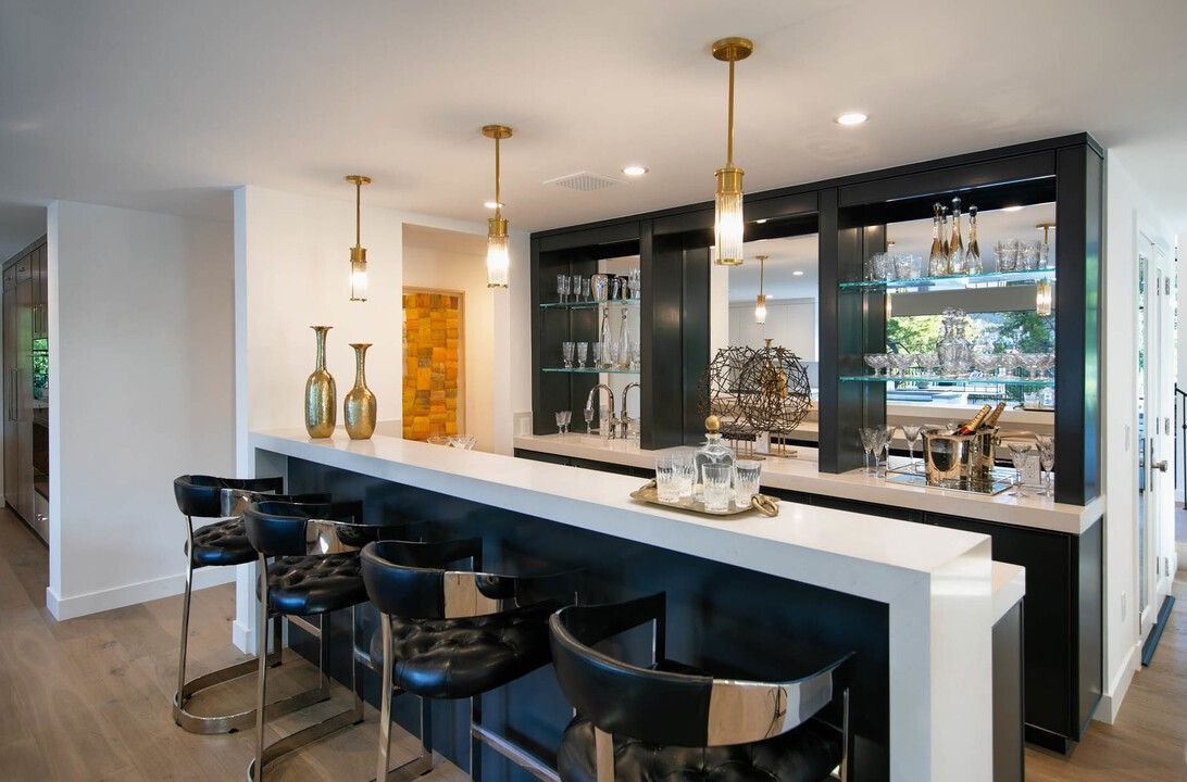 A kitchen with a long bar and stools