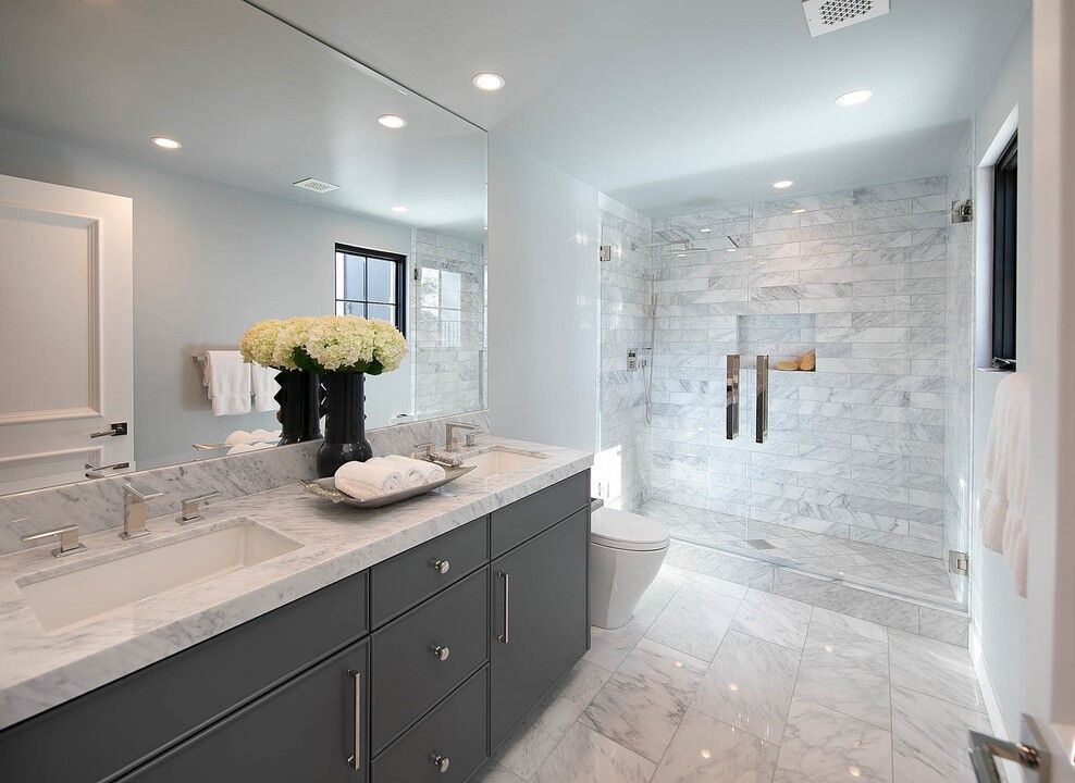 A bathroom with two sinks and a walk in shower.