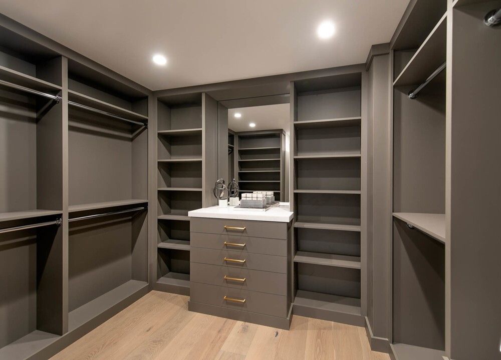 A walk in closet with lots of shelves and drawers and a mirror.