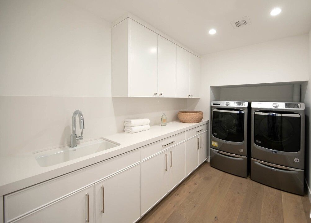 A laundry room with a sink and two washers and dryers