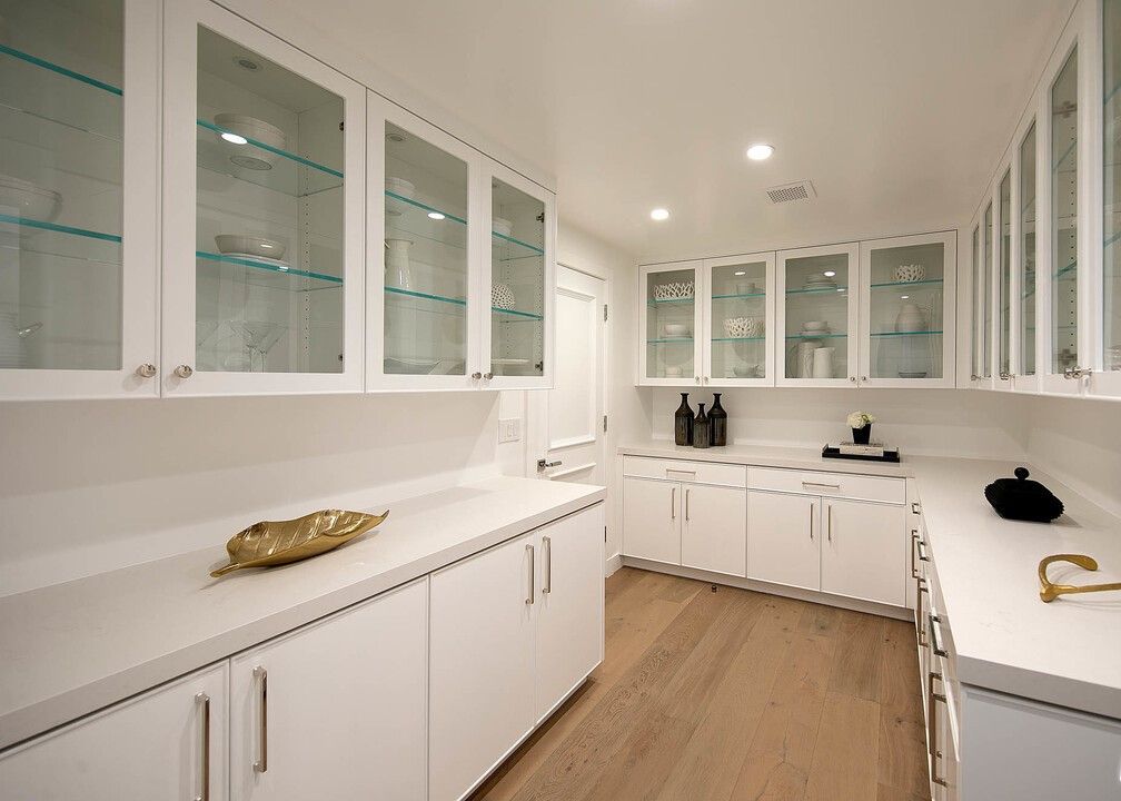 A kitchen with white cabinets and glass doors