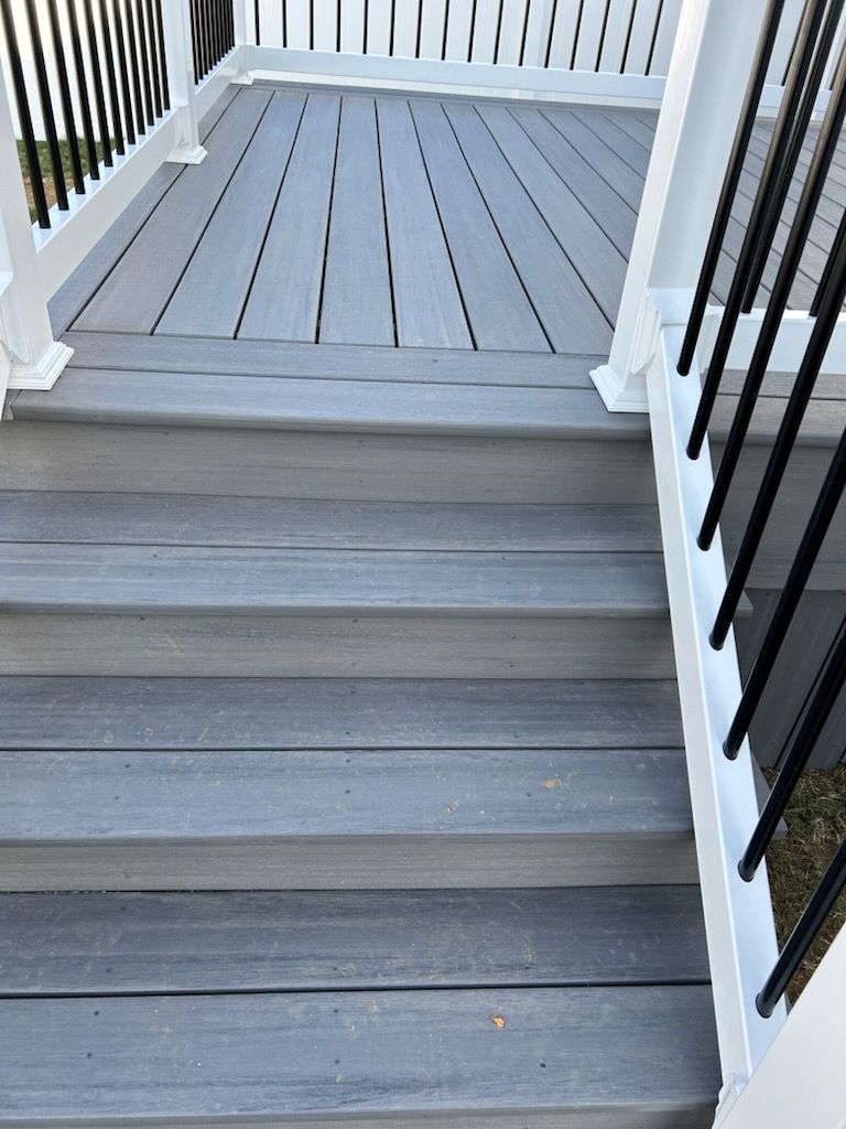 A set of stairs leading up to a deck with a white railing.