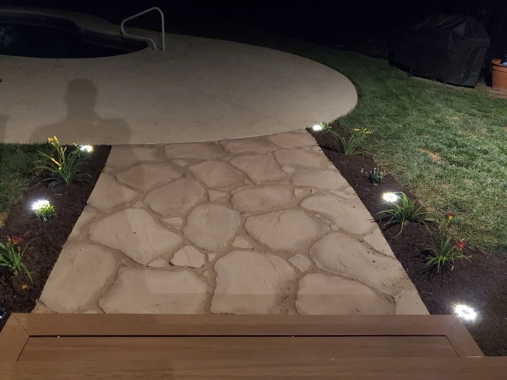 A stone walkway leading to a pool at night.
