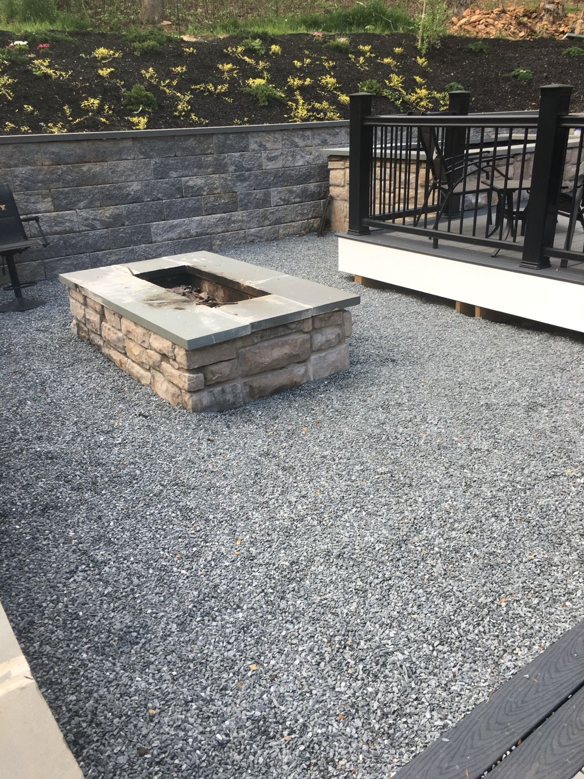 A fire pit is sitting in the middle of a gravel patio.