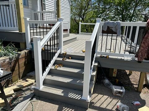 A deck with stairs and a white railing is being built.