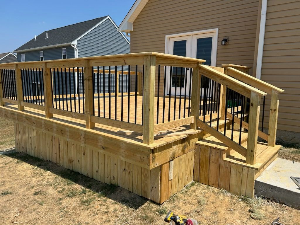 A wooden deck with stairs and railing is in front of a house.