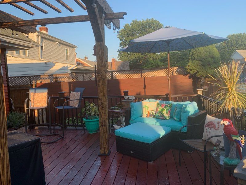 A deck with a couch , chairs , table and umbrella.