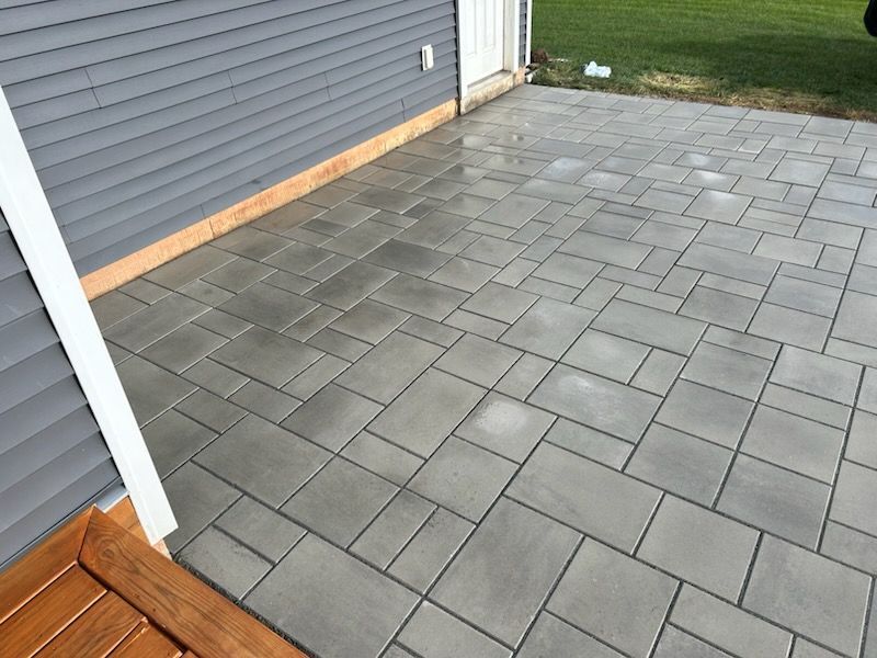 A patio with a wooden deck in front of a house.