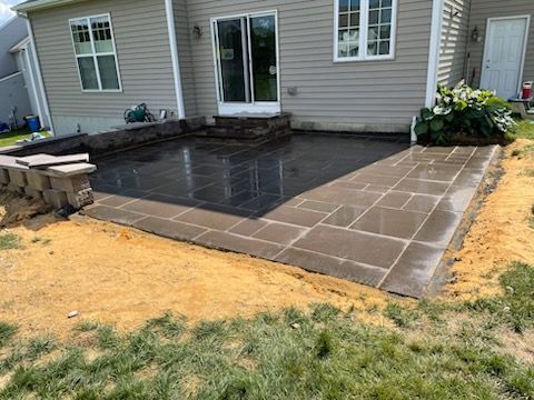 A patio is being built in the backyard of a house.